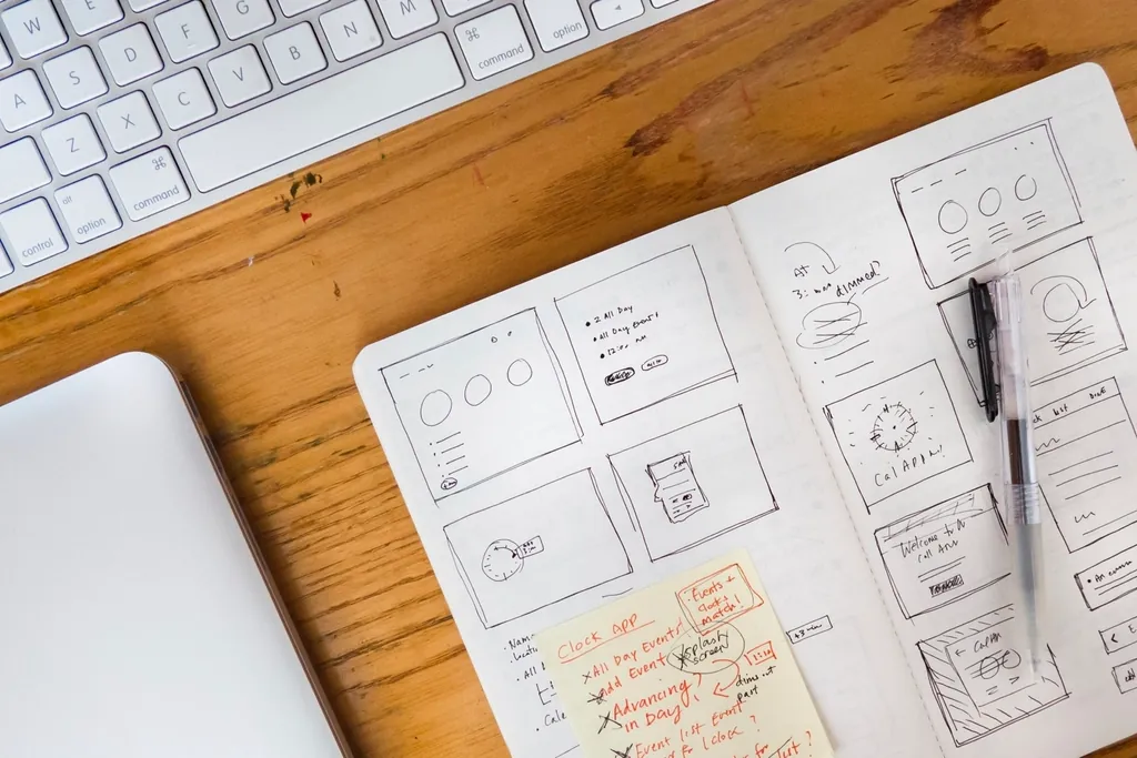 Website wireframes sketched in a notebook by a keyboard