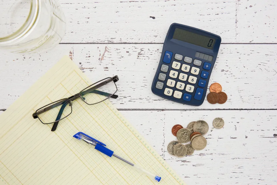 Calculator, coins, and a ledger pad