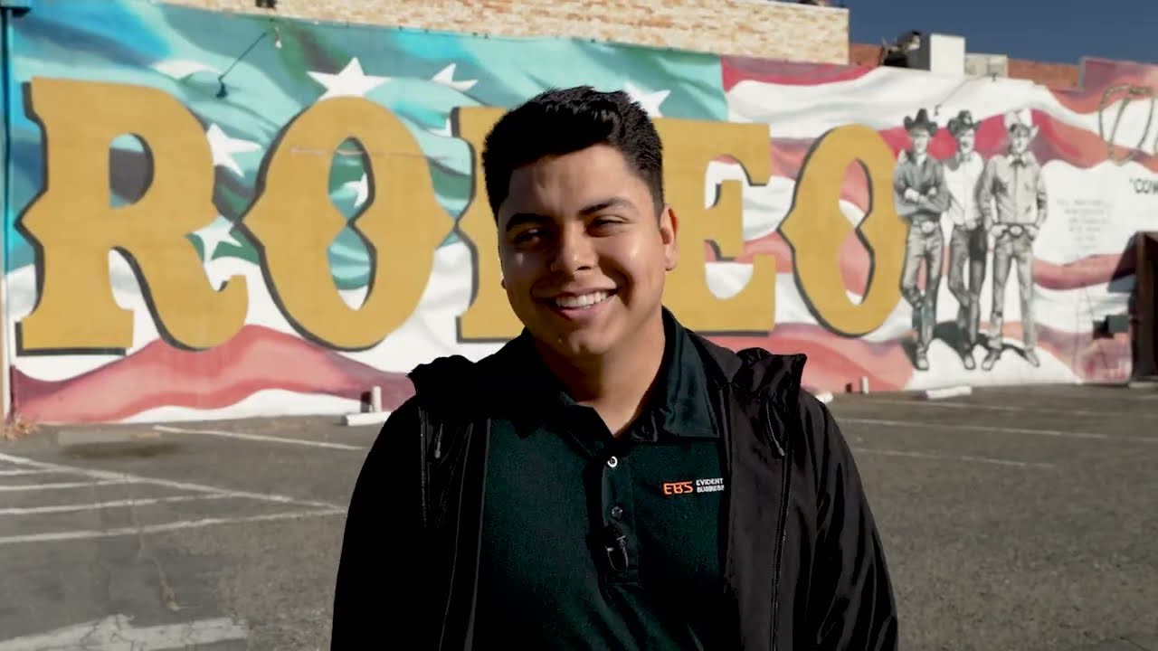 Manuel from Evident Business Solutions in front of a rodeo mural